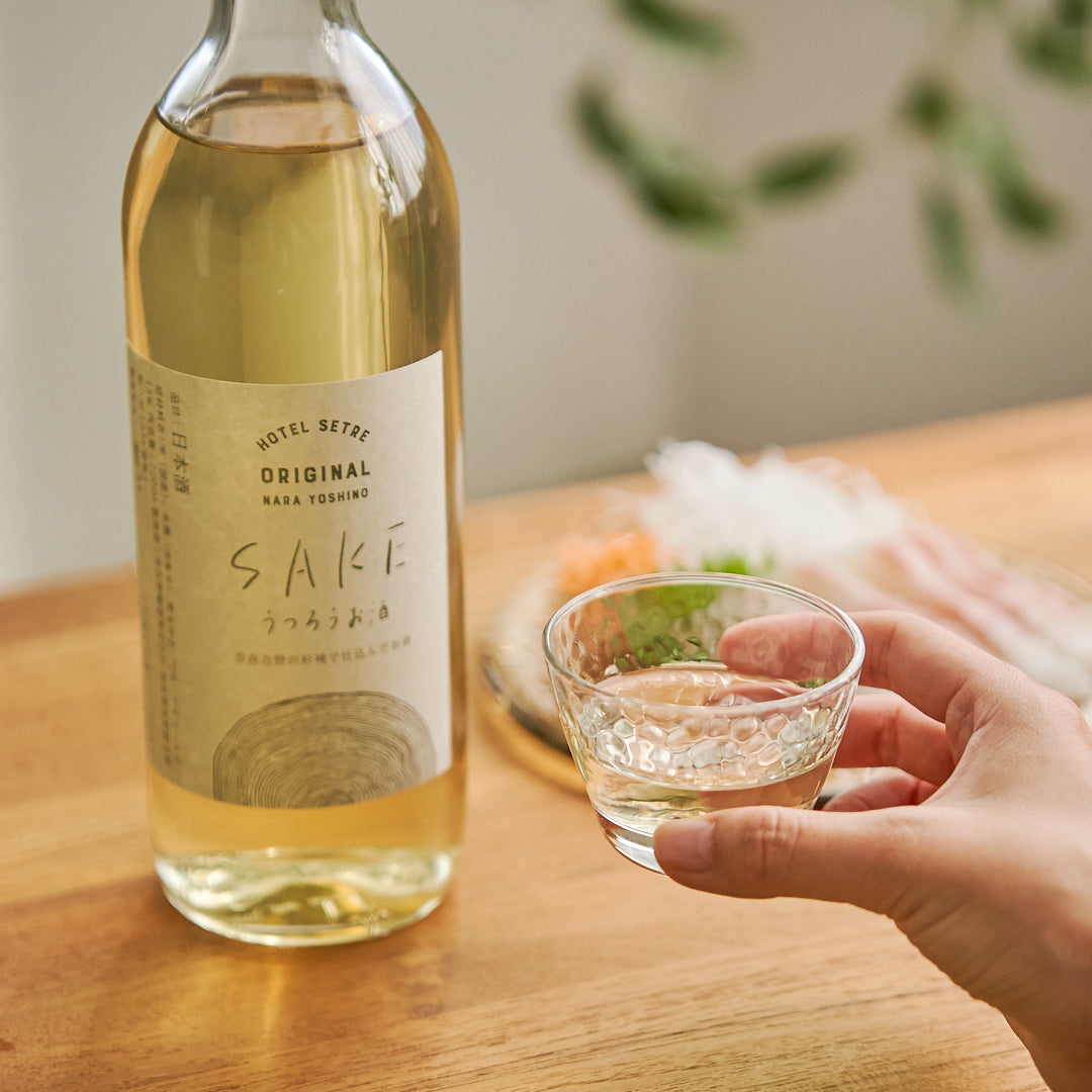 うつろうお酒と美味しそうな鯛の刺し身とお猪口を持ち上げている手の様子